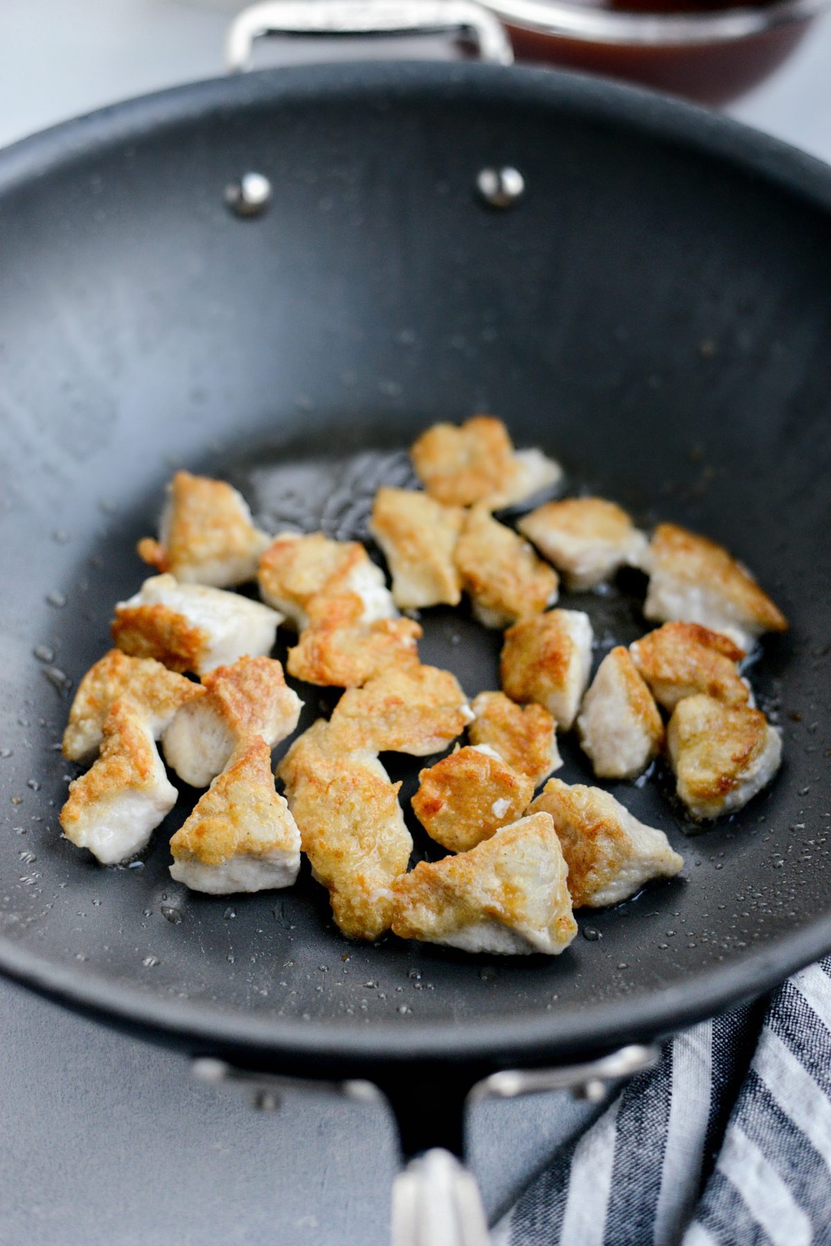 wok with oil and browned chicken