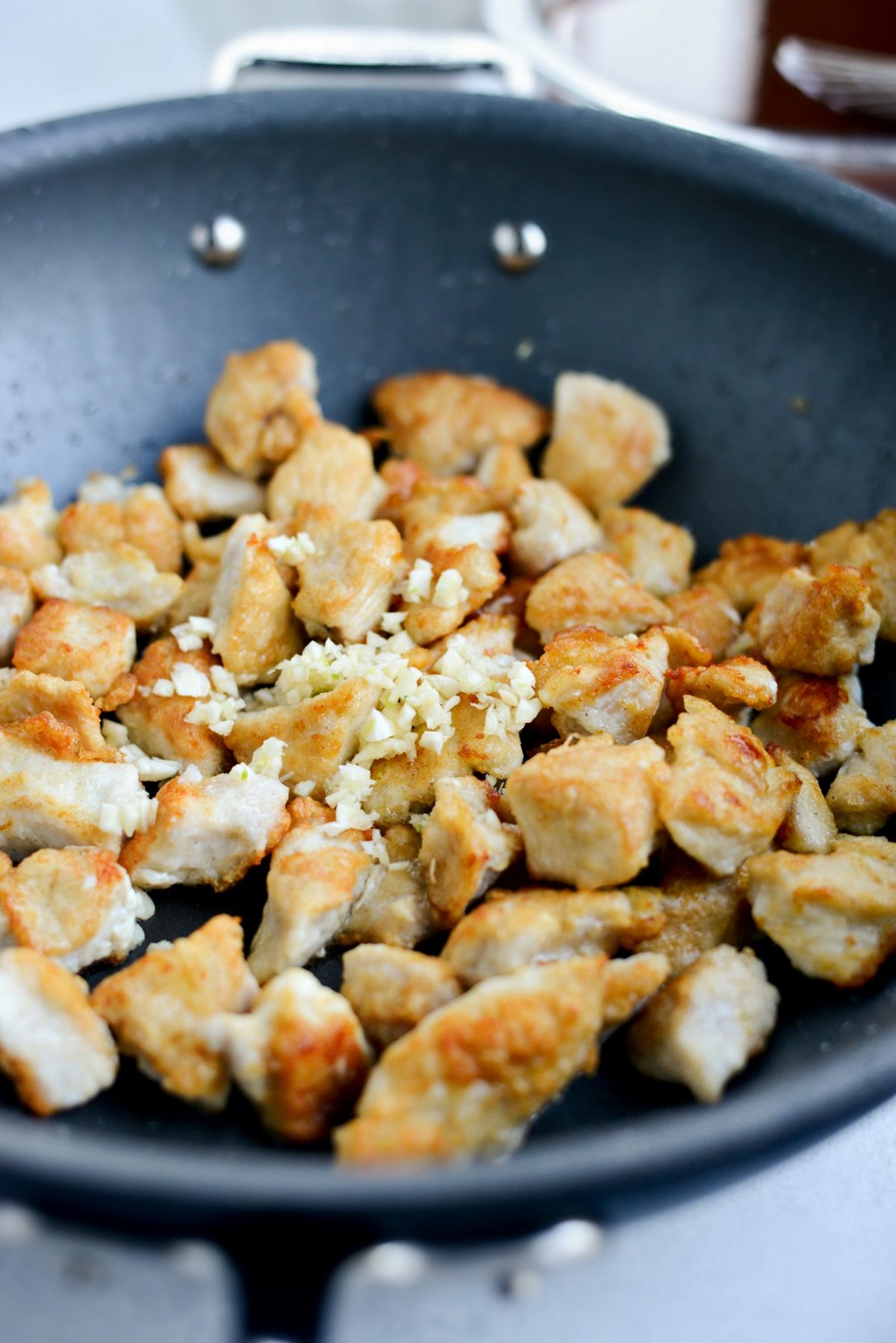 minced garlic added to pan of crispy browned chicken 