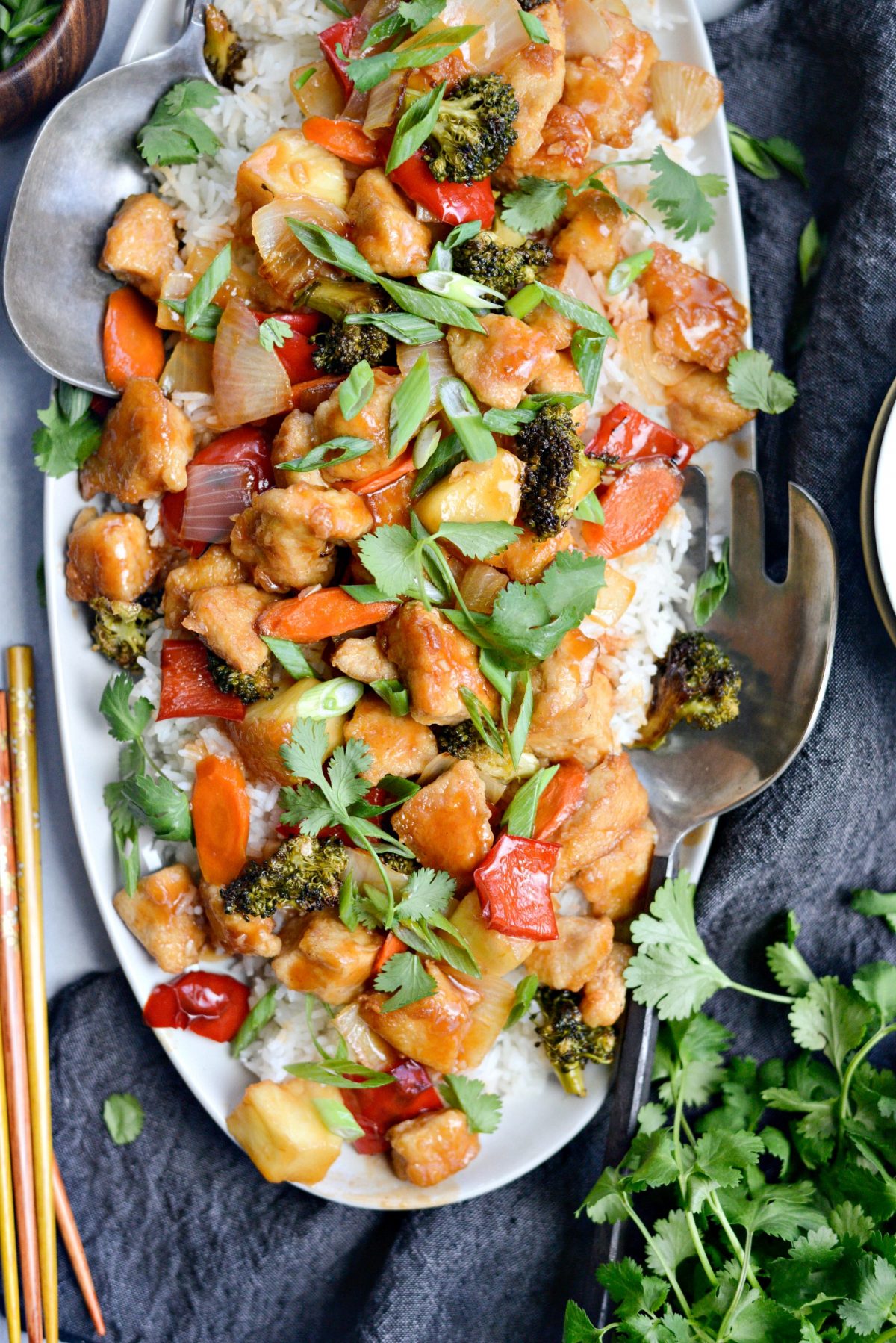 top down photo of Homemade Sweet and Sour Chicken with serving utensils. 