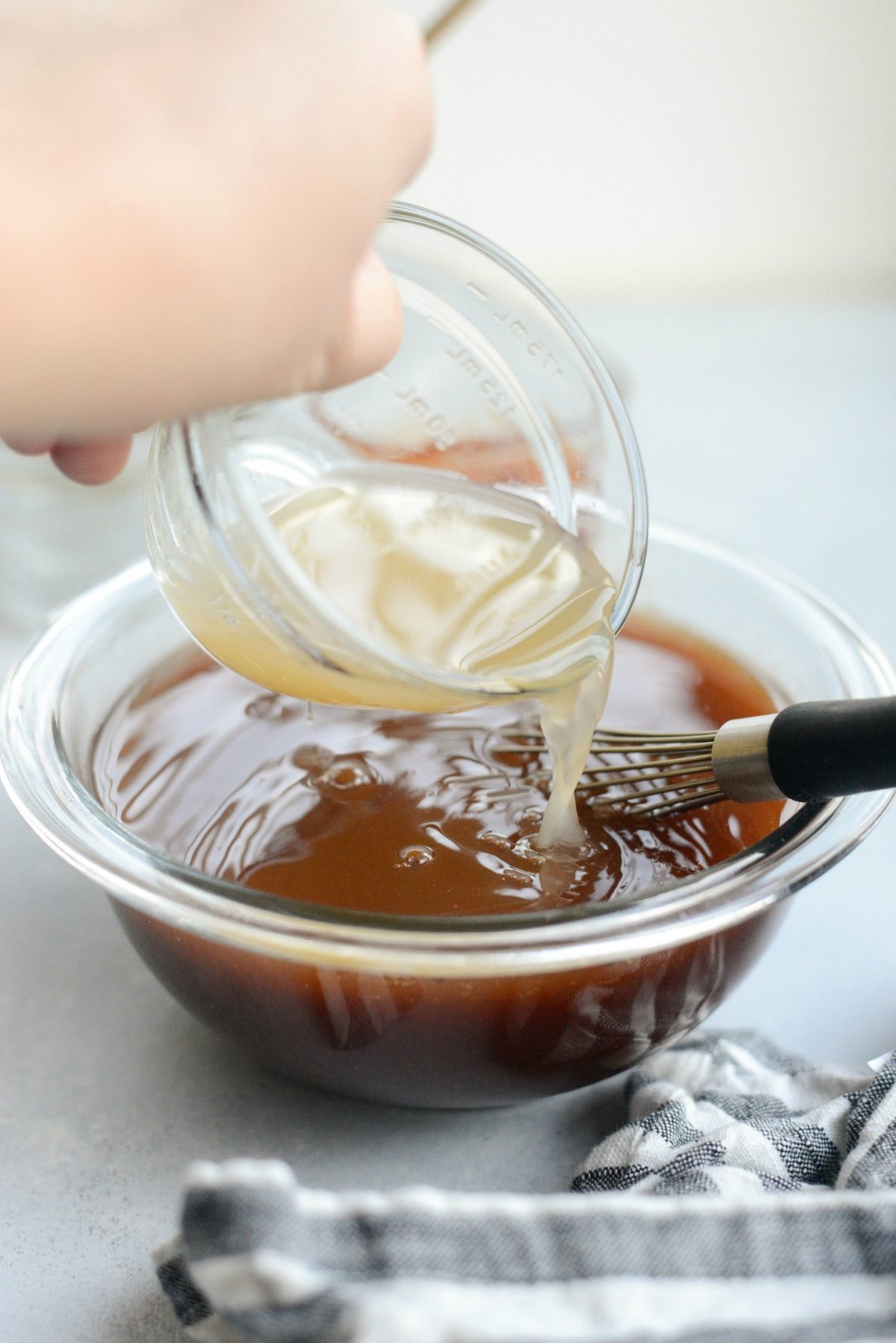 pouring low-sodium chicken broth into sweet and sour sauce.