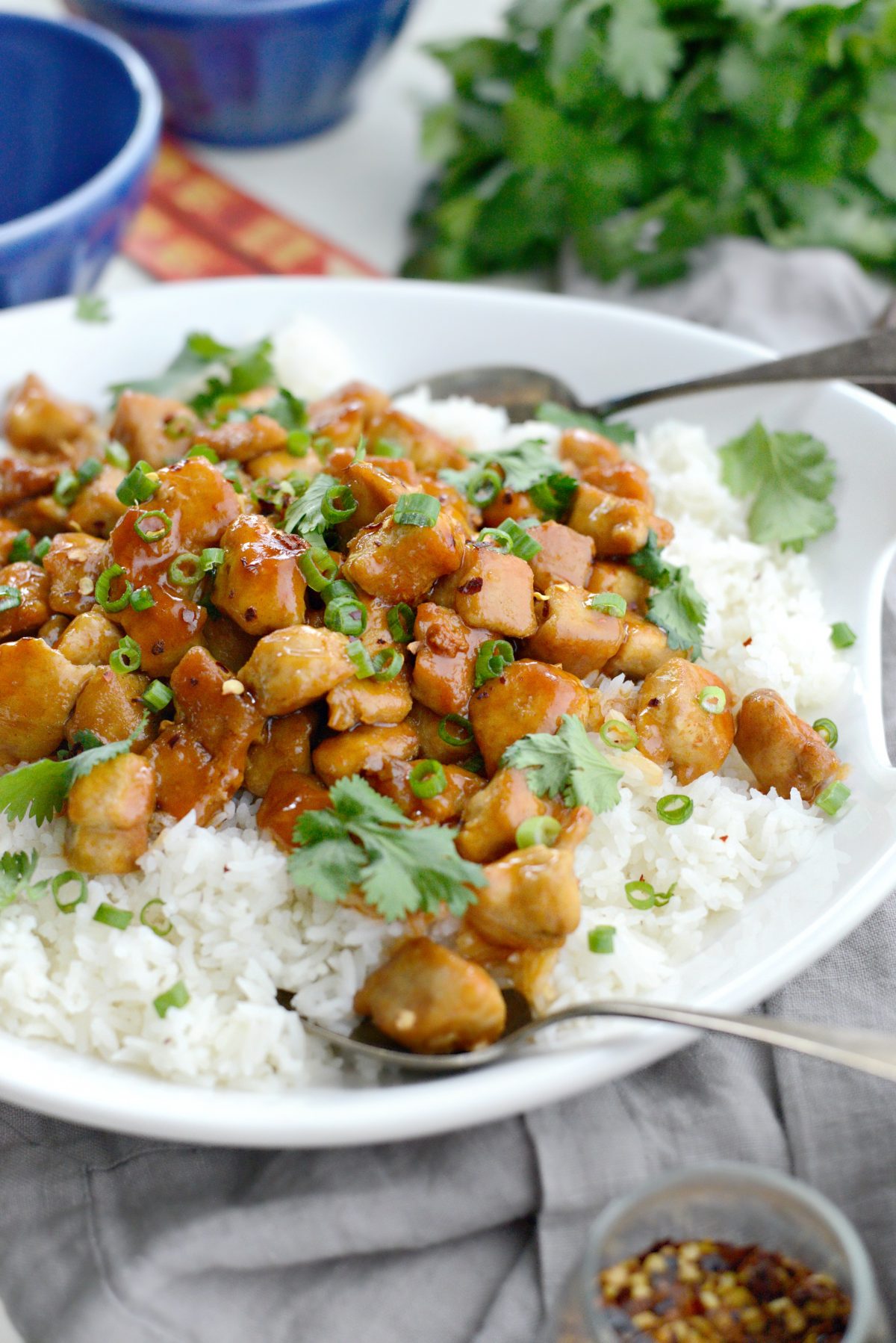 Firecracker Chicken in white bowl with serving spoons