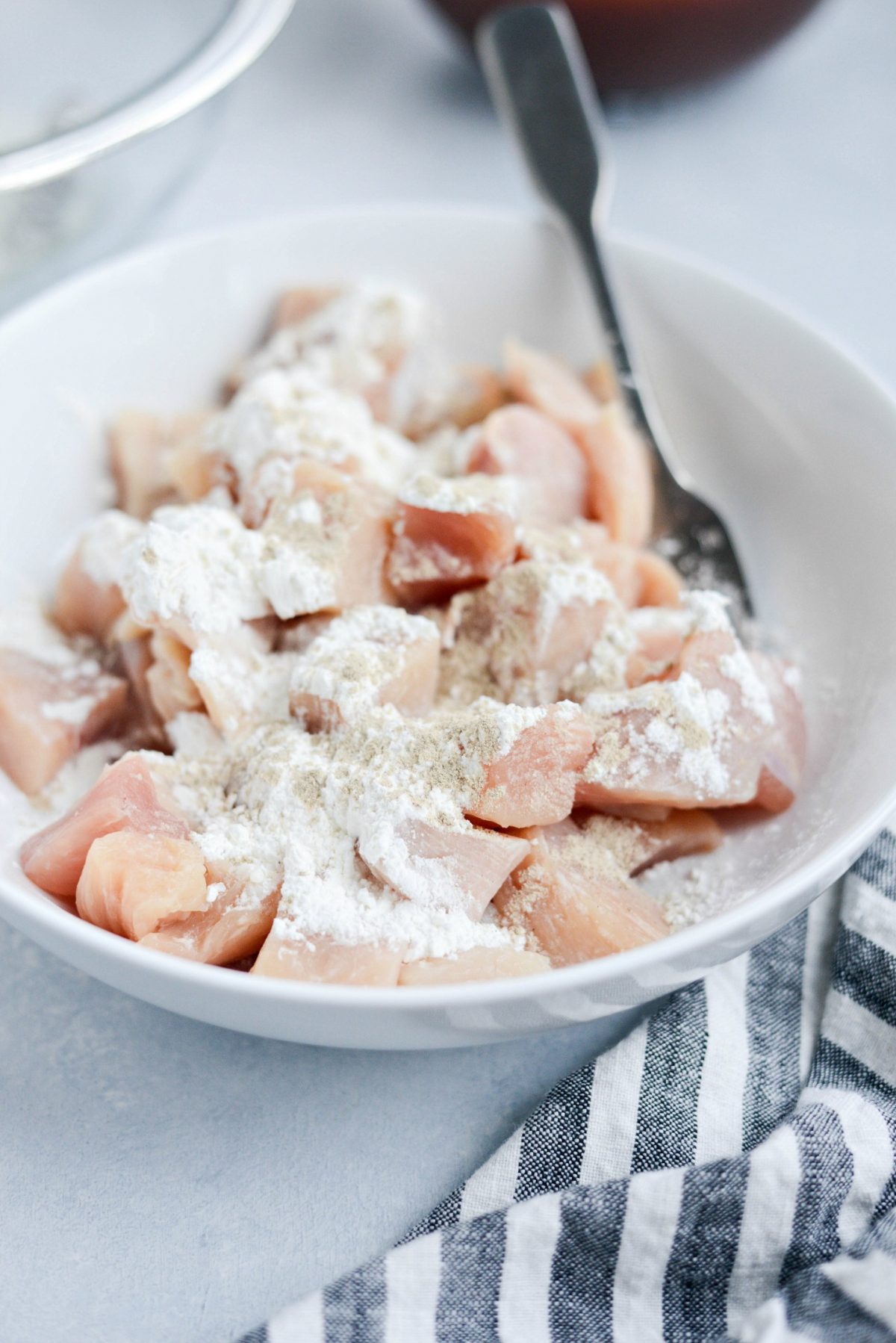 White bowl with chopped chicken, corn starch and ground white pepper.