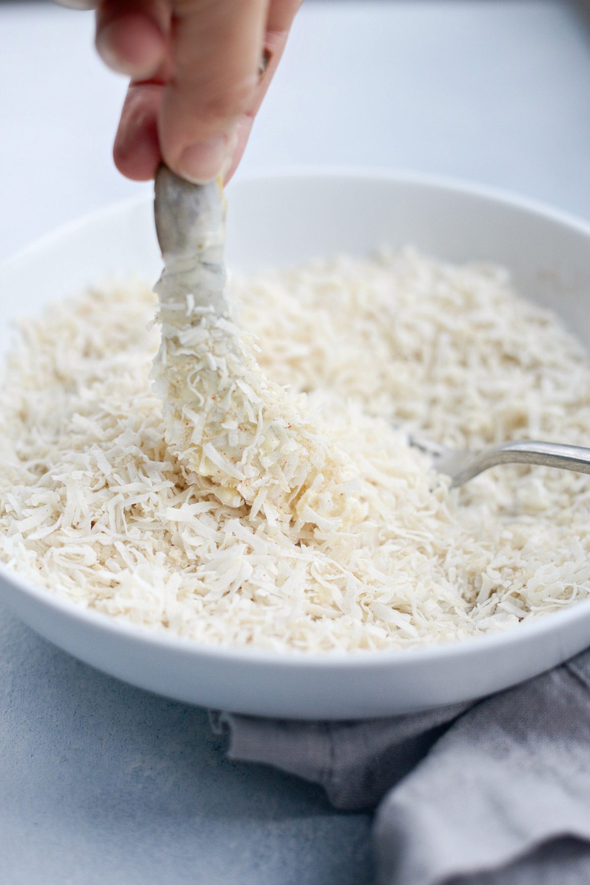 dipping coated shrimp in coconut breading