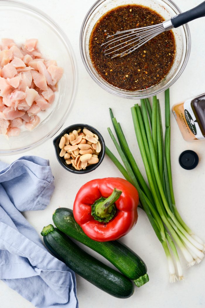 bowl of diced chicken, kung pao sauce, peanuts, green onions, red pepper, zucchini, peanut oil