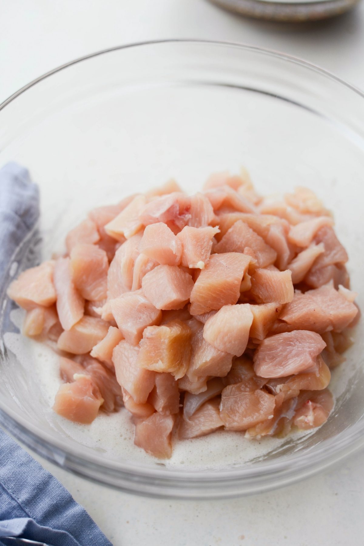 diced chicken in glass bowl with whipped egg whites.