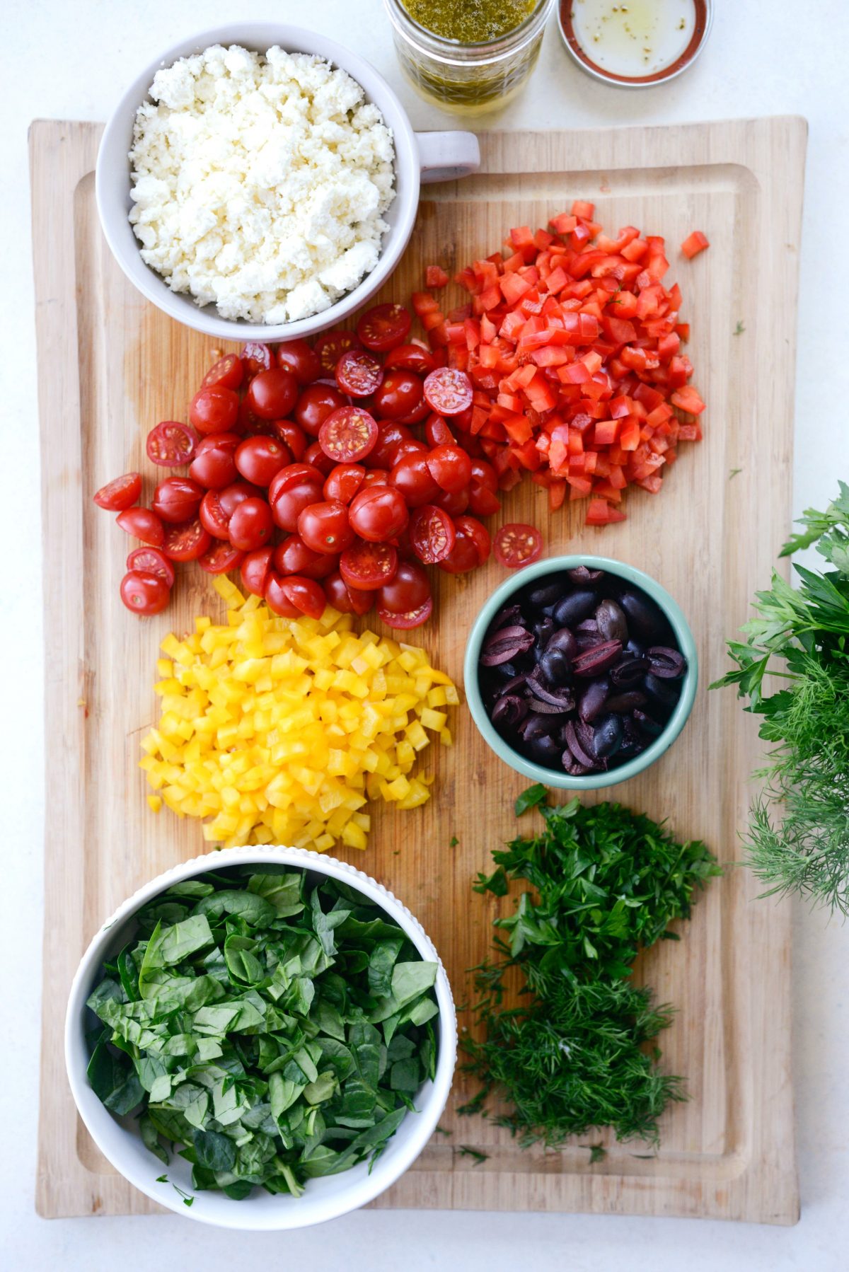 prepped salad ingredients on wood cutting board.