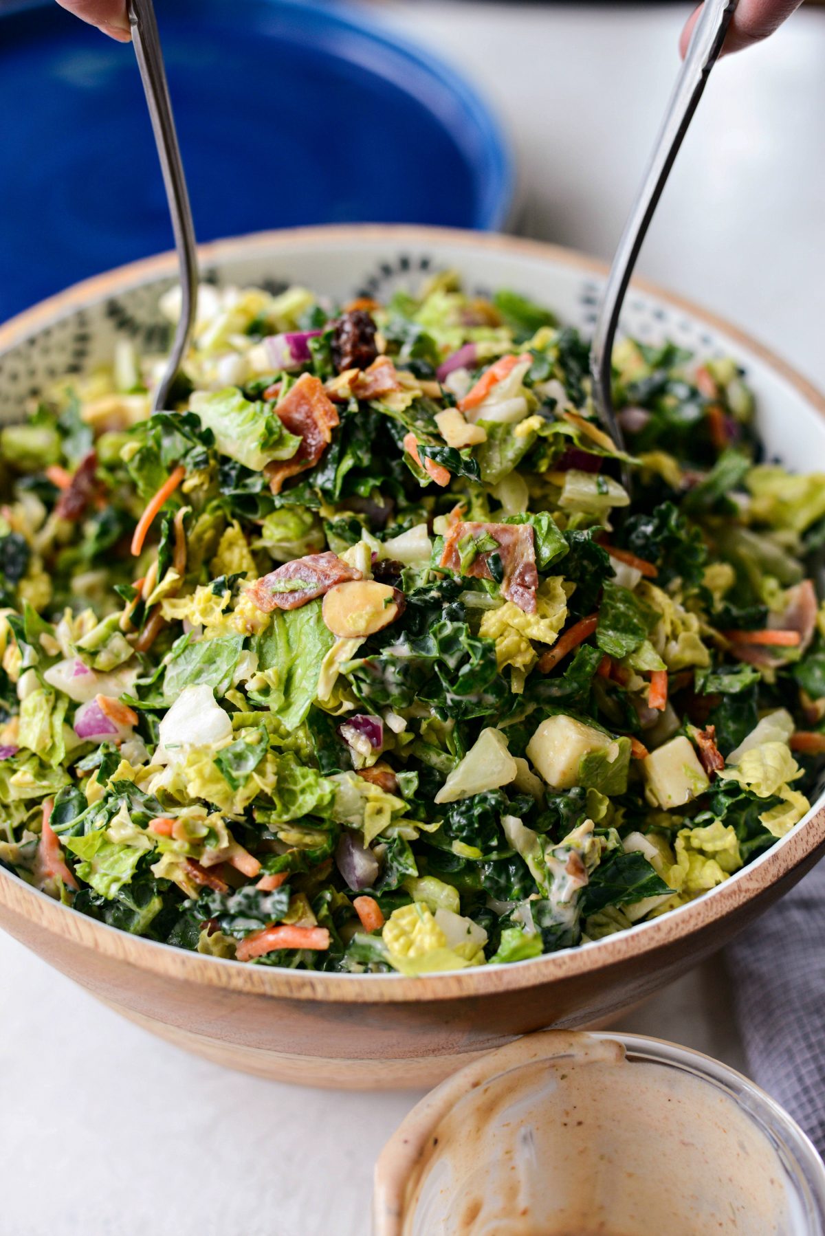 BBQ Ranch Chopped Salad is being tossed with metal utensils.