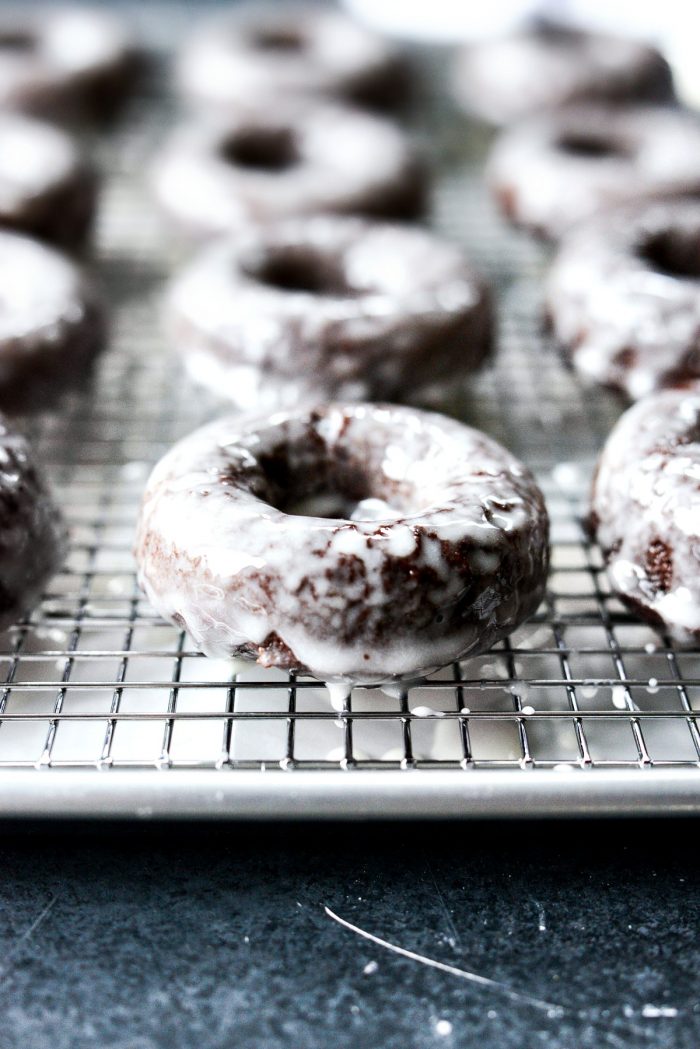 glazed chocolate cake doughnut on wire wrack to set glaze.