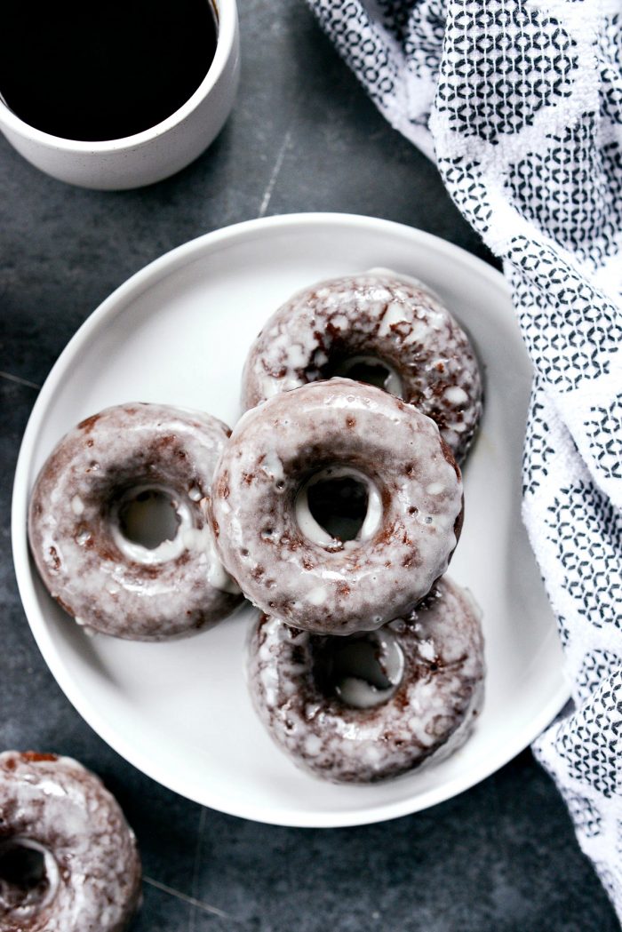 Glazed Chocolate Cake Doughnuts on a white plate with coffee