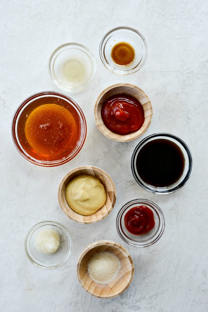 top down photo of the sauce ingredients: honey, coconut aminos (or tamari or soy sauce), ketchup, dijon mustard, grated garlic, sriracha, apple cider vinegar, Worcestershire sauce, onion powder