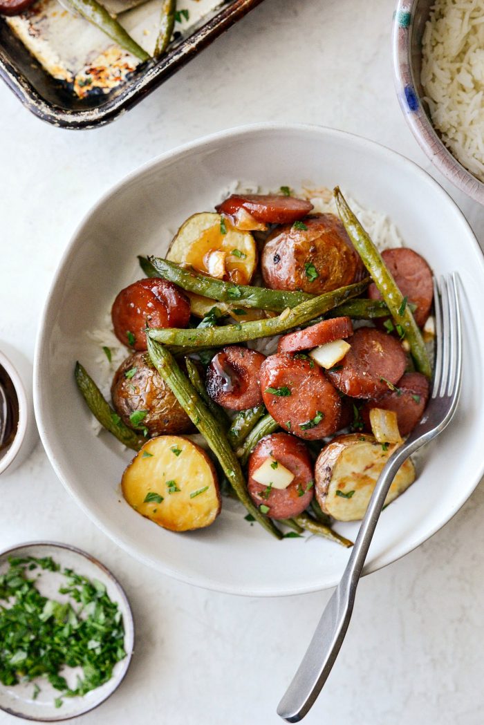 Honey Barbecue Sausage Sheet Pan Dinner - sausage, green beans and potatoes in white bowl with parsley