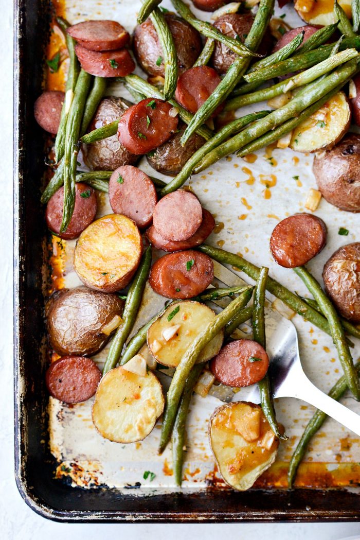 Honey Barbecue Sausage Sheet Pan Dinner - metal spatula serving saucy, sausage, potatoes and green beans.
