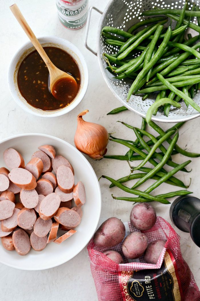 Top down shot of ingredients like sausage, potatoes, onion, green beans and honey barbecue sauce.