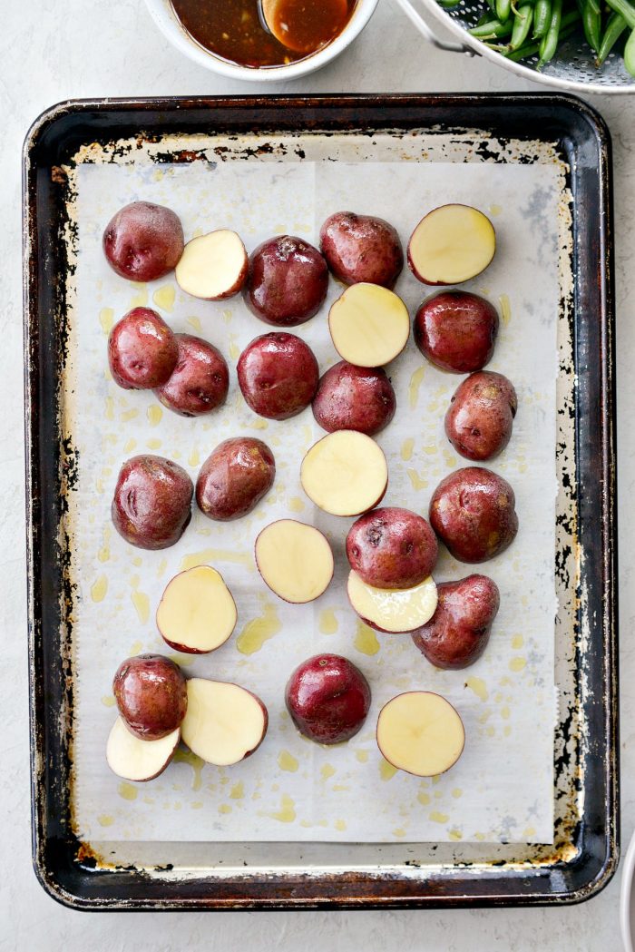 sheet pan, lined with parchment paper and potatoes with olive oil drizzled over top