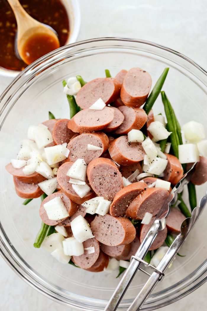 bowl of sliced sausage, diced yellow onion, green beans, salt and pepper