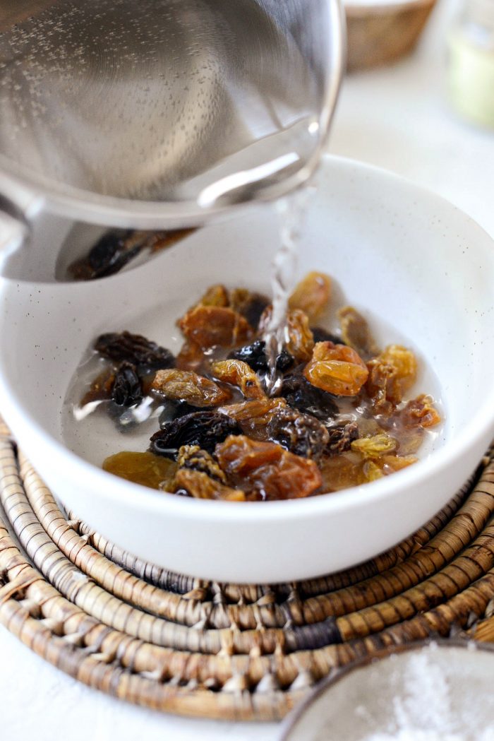 hot water pouring over raisins in white bowl.