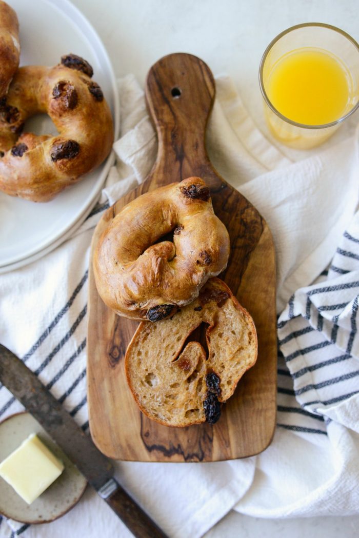 sliced and toasted cinnamon raisin bagel on wood cutting board