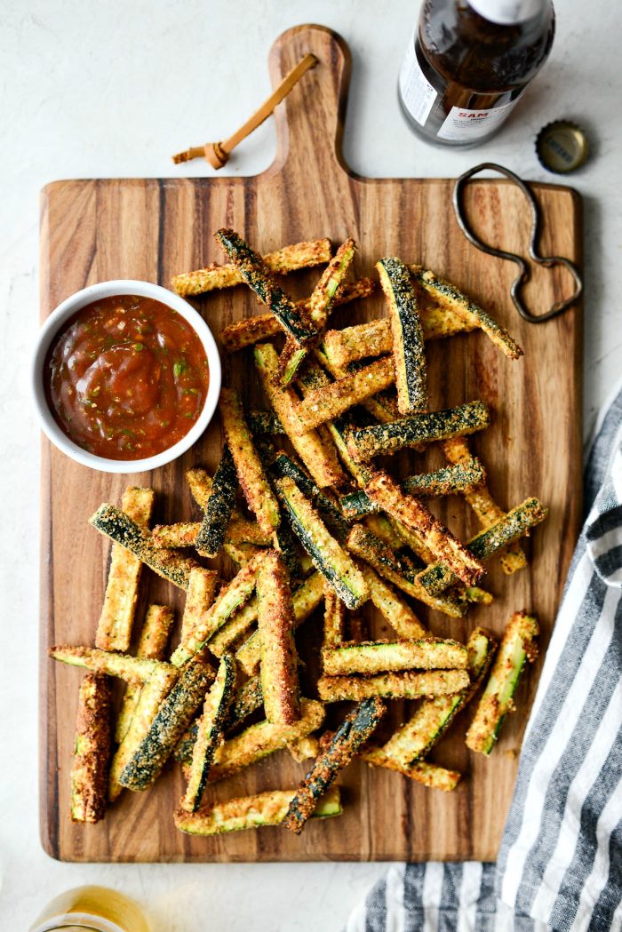 Air Fryer Zucchini Fries - top down shot of wood cutting board with zucchini fries, basil ketchup and a bottle of beer.