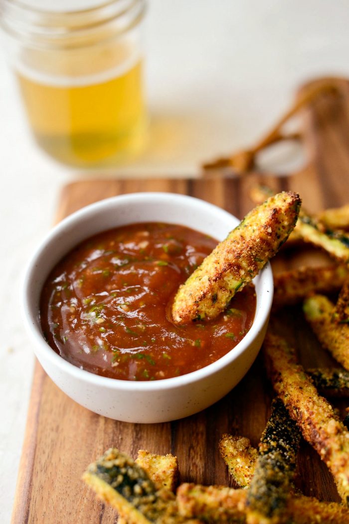 Air Fryer Zucchini Fries - close up of zucchini fry in bowl of basil ketchup.