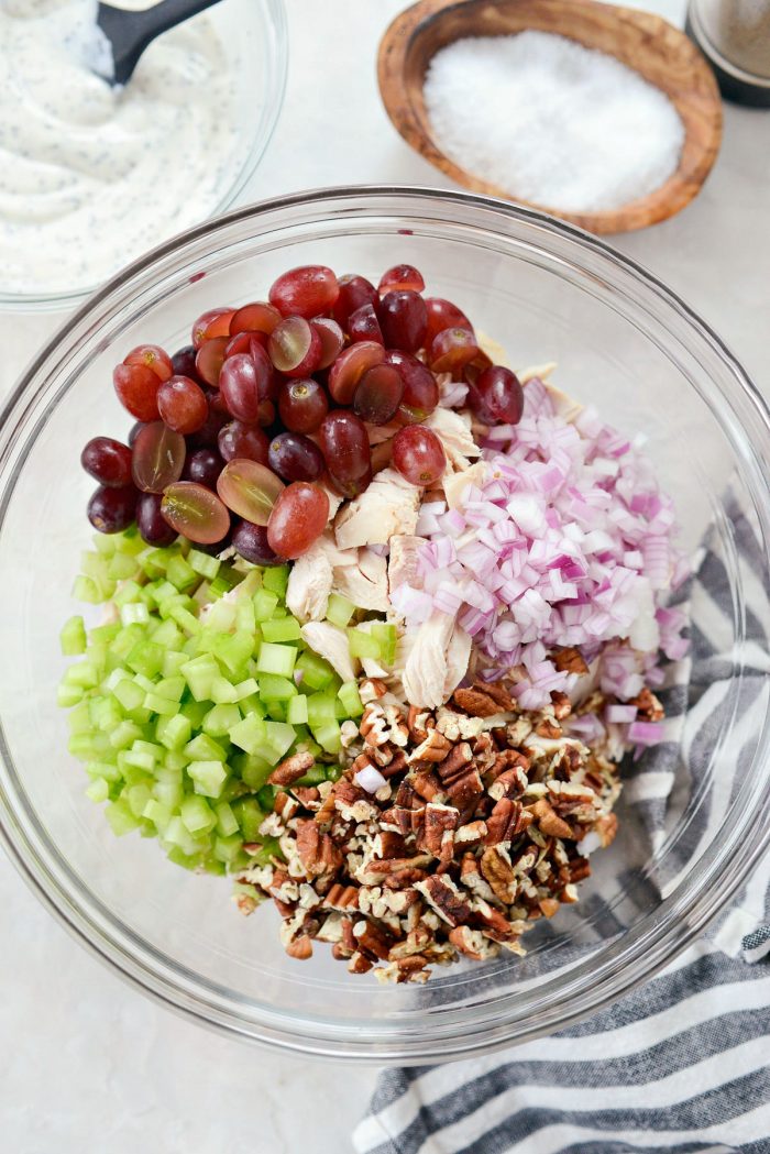 Mixing bowl with cooked chicken, grapes, celery, onion and chopped toasted pecans.
