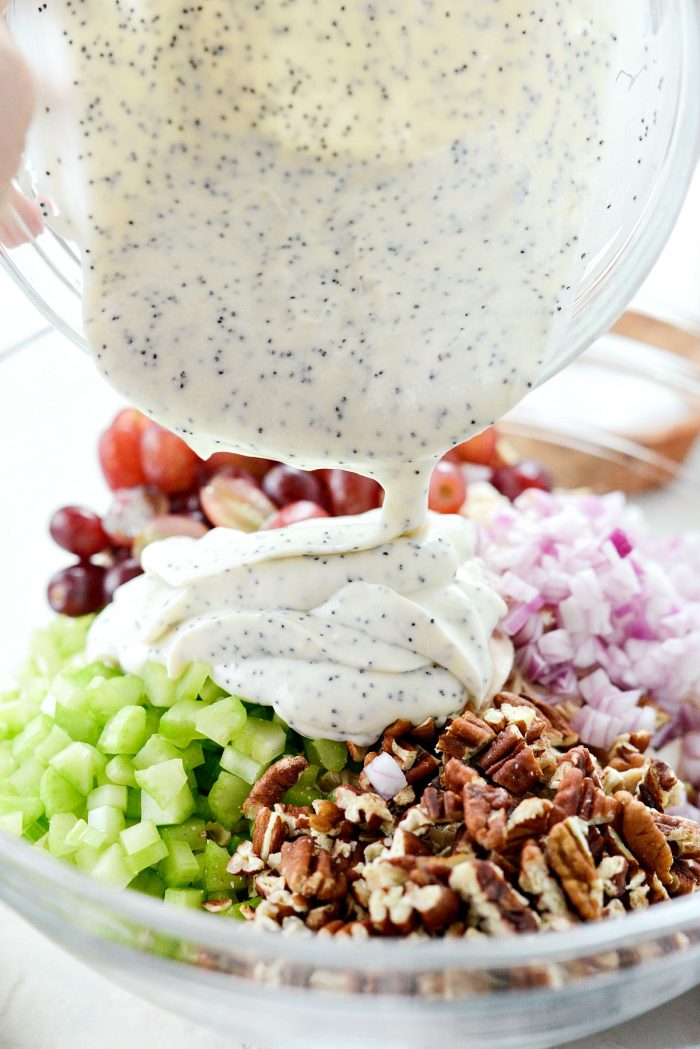 pouring dressing into bowl with salad ingredients.