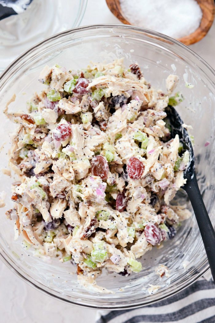 Salad mixed with dressing in clear bowl.