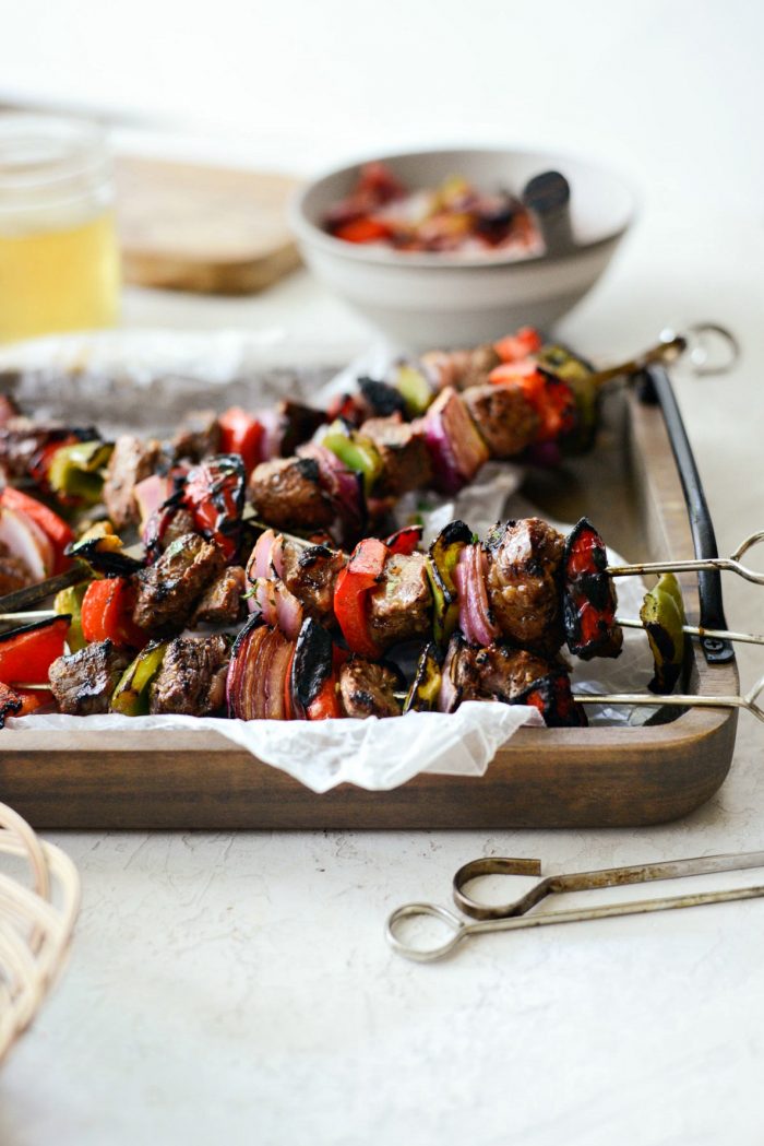 side shot of grilled marinated steak kebabs on wooden tray