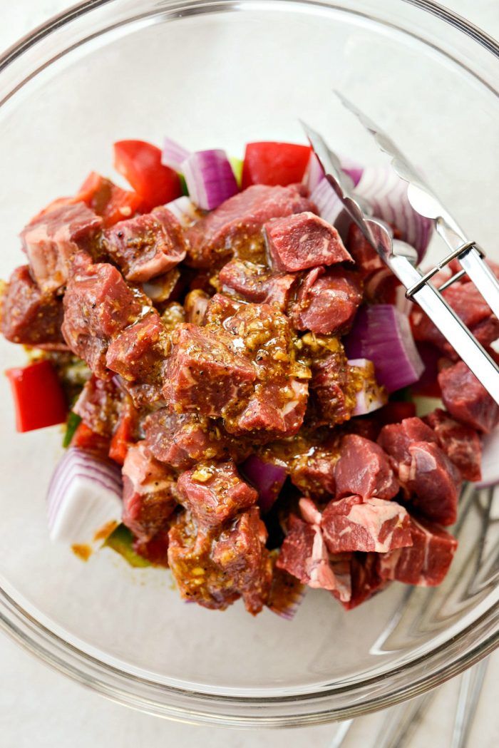 top don shot of large chopped peppers and onions in glass bowl with marinade.