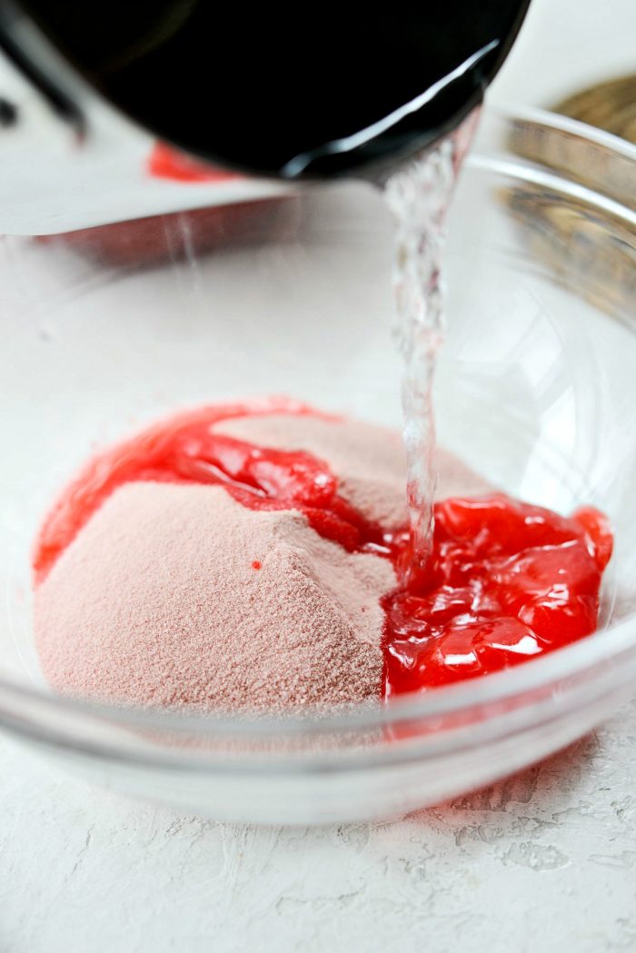 boiling water being added to a bowl of strawberry jell-o mix.