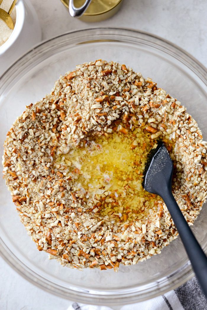 pouring butter into the pretzel and almond mixture.