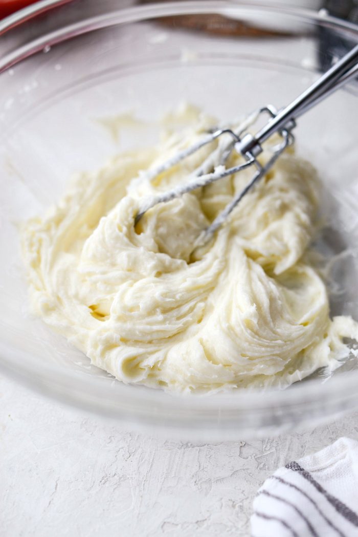 clear mixing bowl with creamed whipped cream, sugar and vanilla extract.
