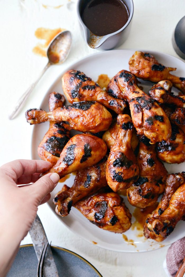 grabbing a piece of easy bbq chicken drumsticks.