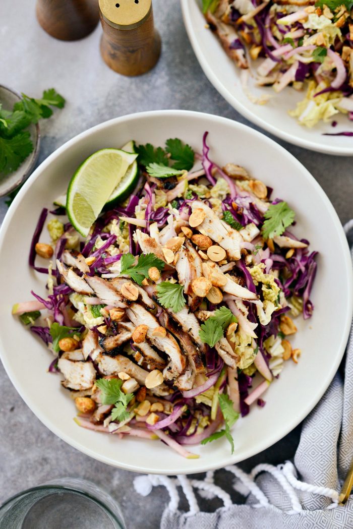 Grilled Thai Chicken Salad in cream bowl with wedges of lime.