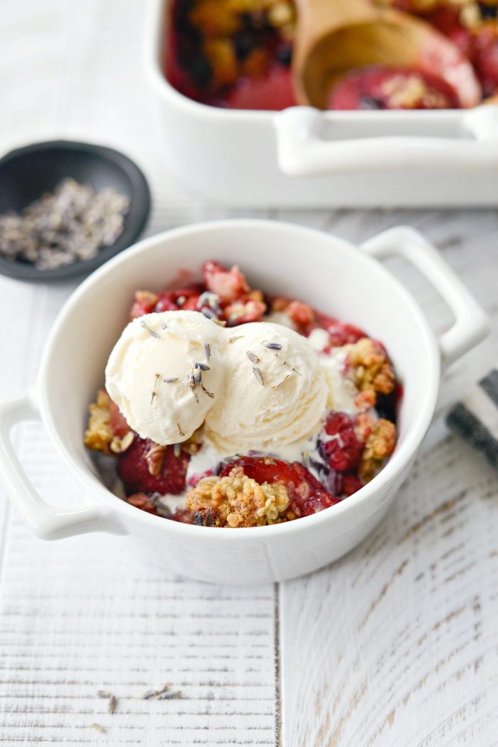 Homemade Berry Crisp Recipe topped with vanilla ice cream and lavender.