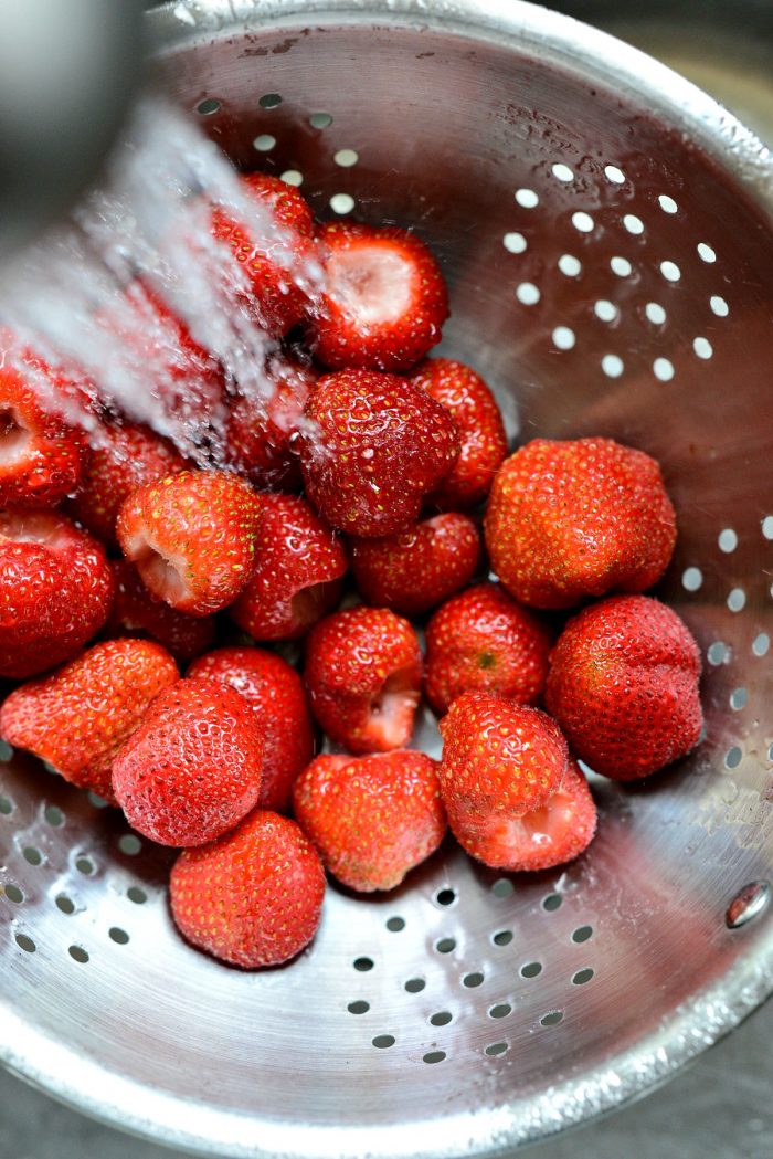 rinsing strawberries in colander.