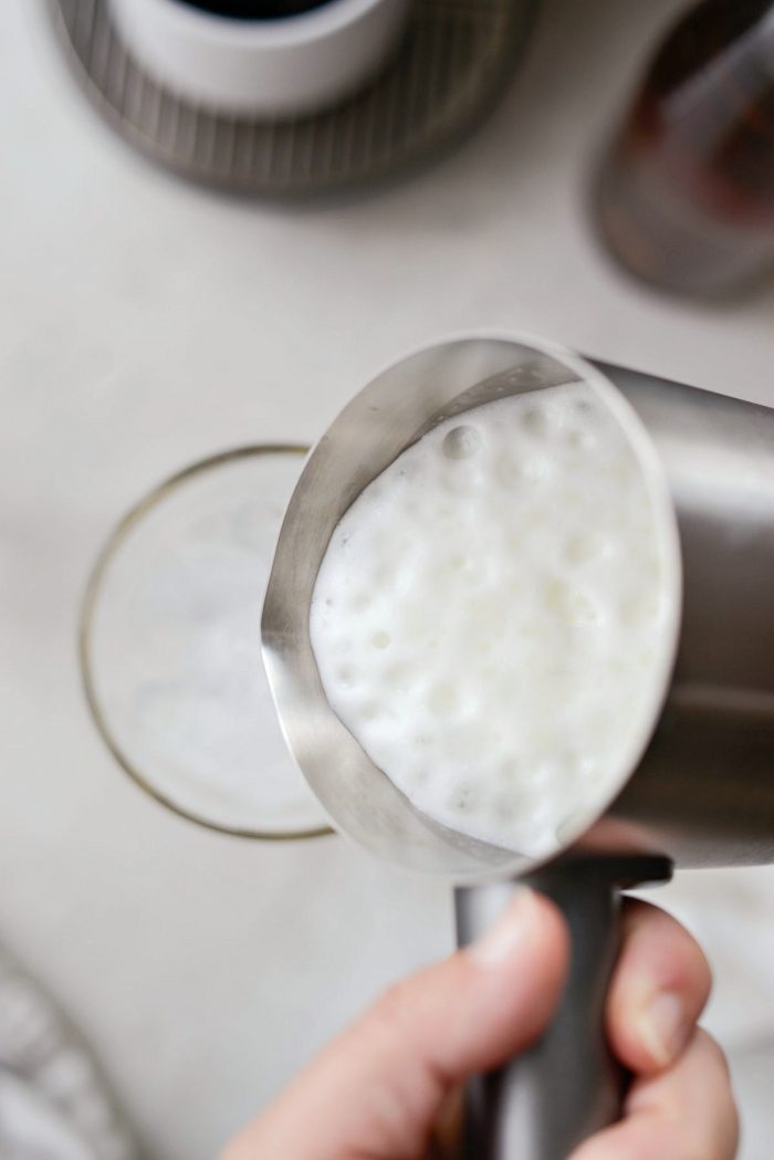 pouring frothed milk into glass.
