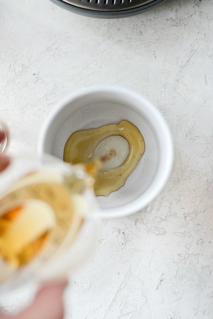 pouring homemade vanilla coffee syrup into small mug.