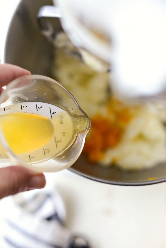 pouring 1 tablespoon fresh orange juice into cake batter.