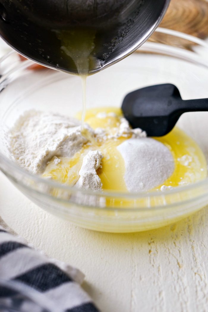 pouring butter into bowl with flour and sugar.