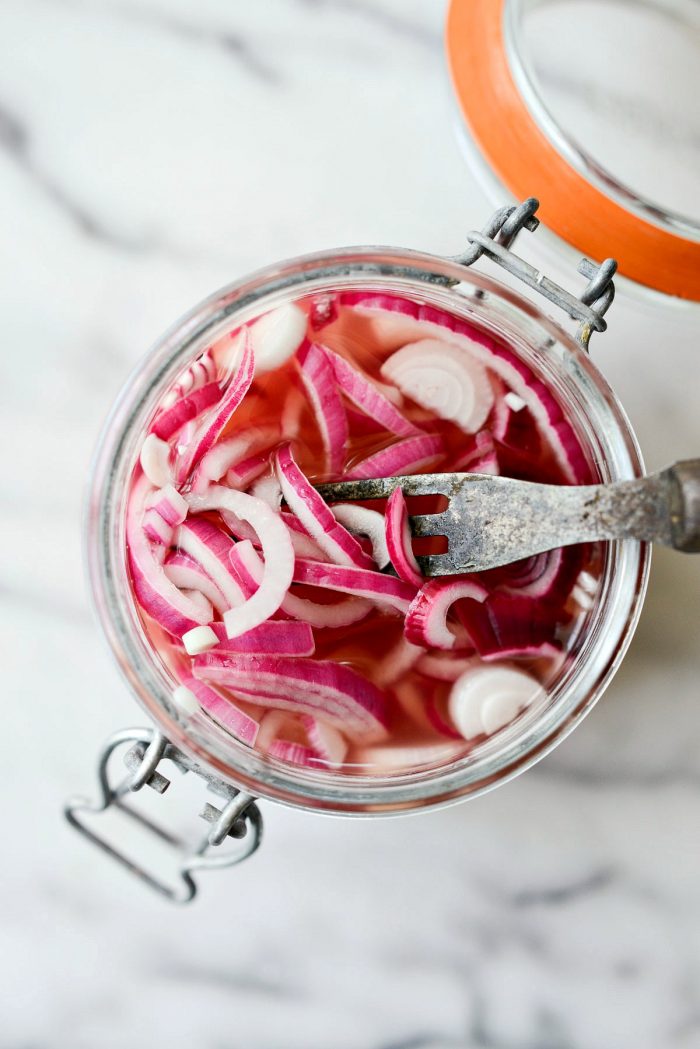 close up of wooden handled fork with pickled red onions.