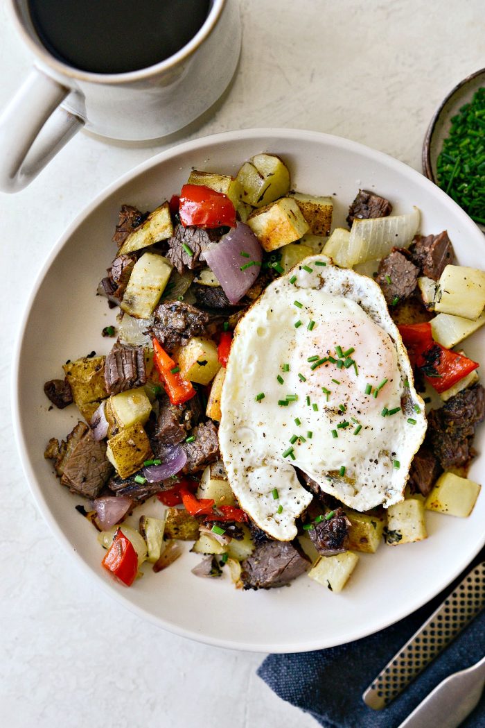 cream bowl of smoked brisket breakfast hash topped with a fried egg.