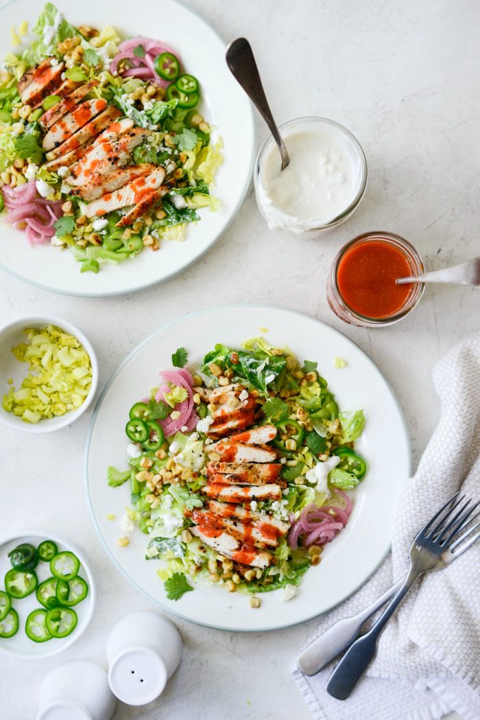 buffalo grilled chicken salad served with jars of buffalo sauce and blue cheese dressing.