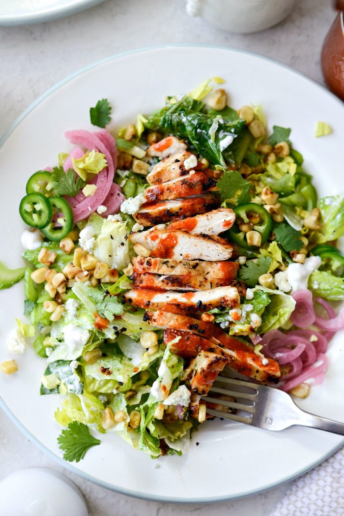 plate of buffalo grilled chicken salad with a forkful bite.