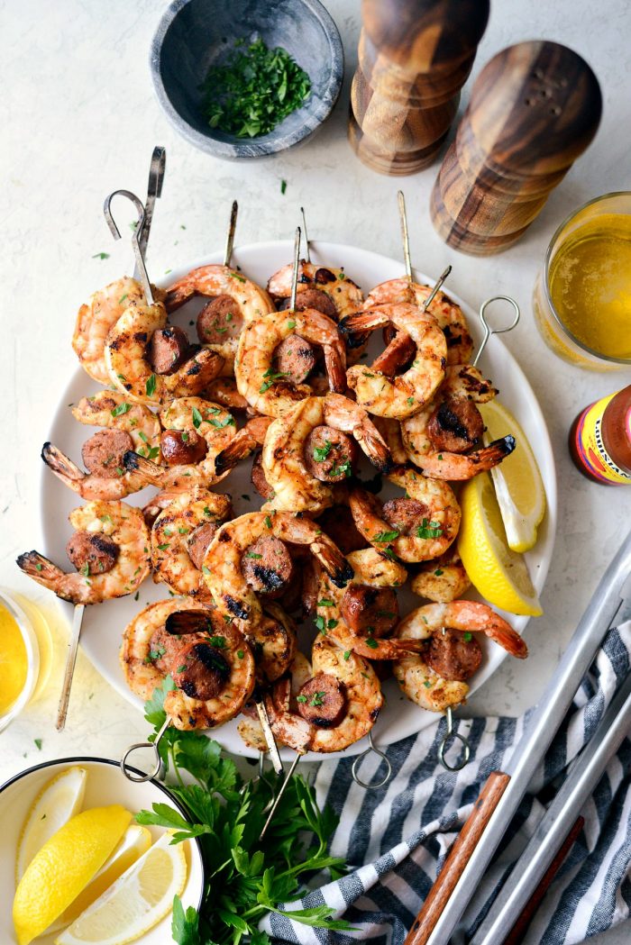 Grilled Cajun Shrimp and Andouille Skewers on white plate sprinkled with minced parsley.