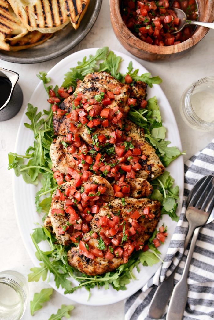 white platter with baby arugula, grilled chicken and bruschetta topping