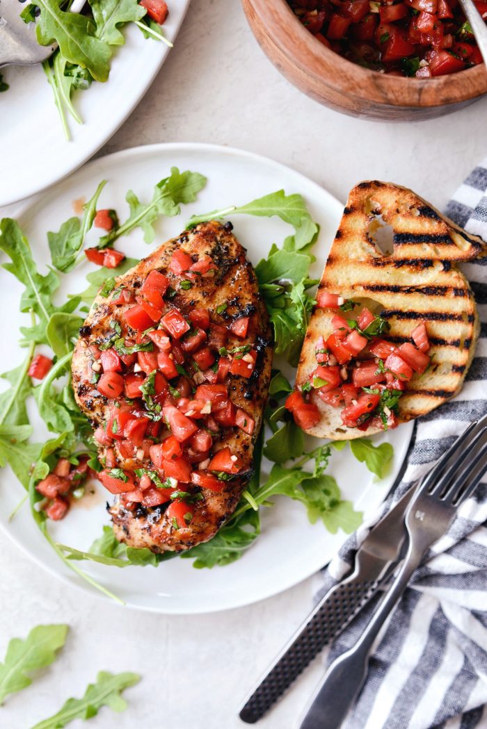 white plate with arugula, grilled chicken bruschetta and grilled bread