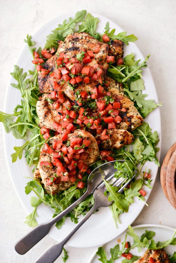 white platter with arugula topped with grilled chicken bruschetta