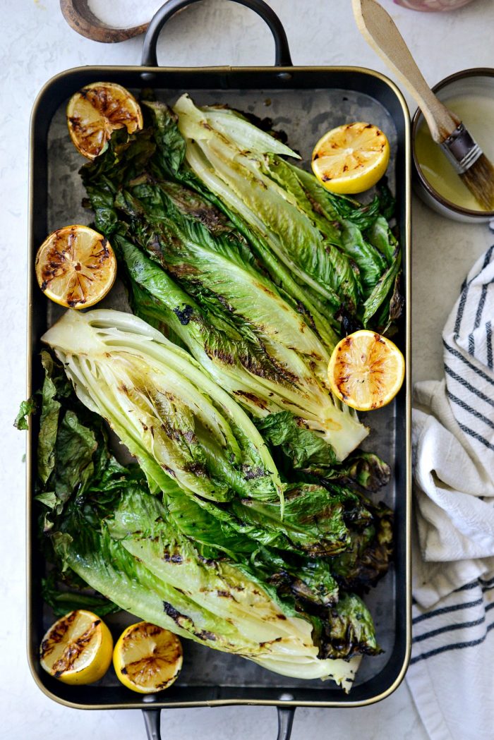 grilled romaine lettuce on a black metal serving tray