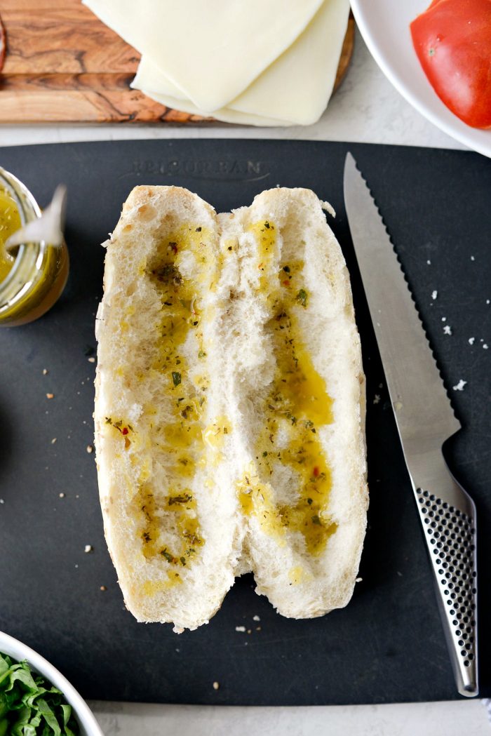 sub bun with dressing drizzled onto the inside of the bread