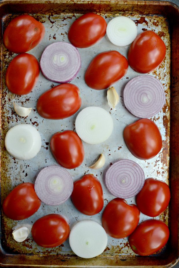 tomatoes onions and garlic on roasting pan.
